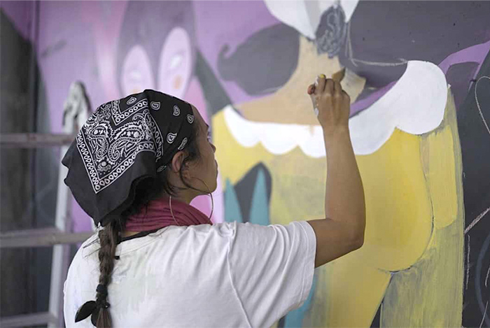 Mujer pintando mural en Centro Arte Alameda